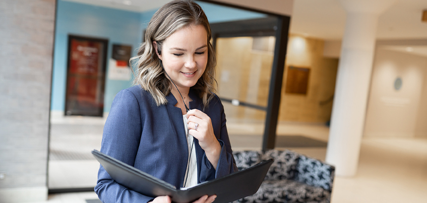 Woman with earpiece and holding a folder